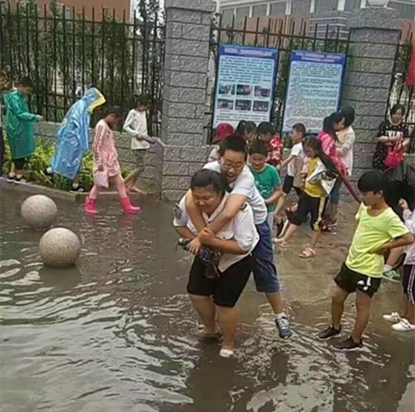 聊城：大雨過(guò)后校門(mén)口積水，95年女校車管理員背38個(gè)孩子上校車