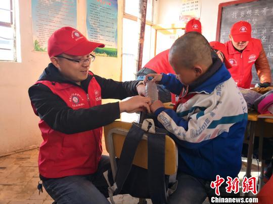 樊恒東(左)給甘肅榆中縣北山的魏家臺教學點小學生送學習用品。 許崗 攝