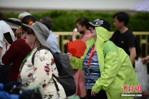 5月22日，在天安門前游玩的外國游客“花式”遮陽。 <a target='_blank' >中新社</a>記者 張興龍 攝