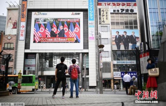 資料圖：2018年6月，在日本東京的一個(gè)廣場(chǎng)，人們通過戶外大屏幕觀看朝美領(lǐng)導(dǎo)人首次會(huì)晤的直播畫面。