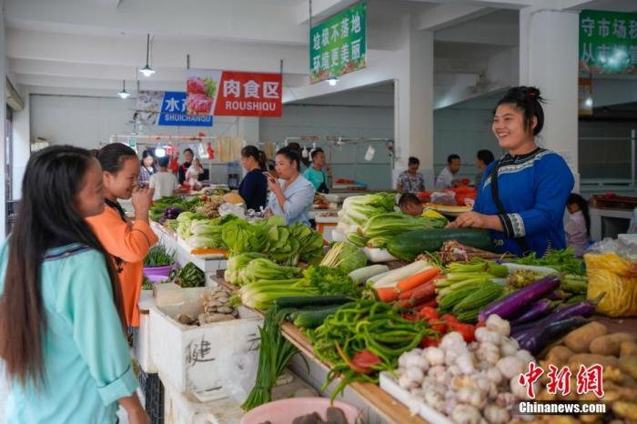 貴州省榕江縣易地扶貧搬遷安置點臥龍小區(qū)，侗族婦女石本艷(右一)在菜市場賣菜。<a target='_blank' >中新社</a>記者 賀俊怡 攝