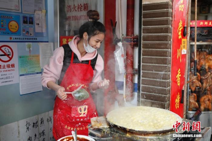 在上海寶山區(qū)一個農(nóng)貿(mào)市場里的一家煎餅鋪，“煎餅西施”黃璐瑤一邊做煎餅，一邊上網(wǎng)直播并與網(wǎng)友交流。 殷立勤 攝